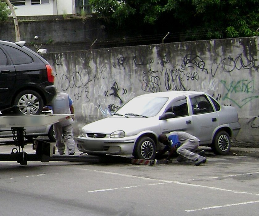 Operador prendendo um carro prata ao guincho para remoção