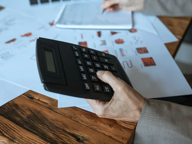Mão com calculadora sobre documentos do contrato